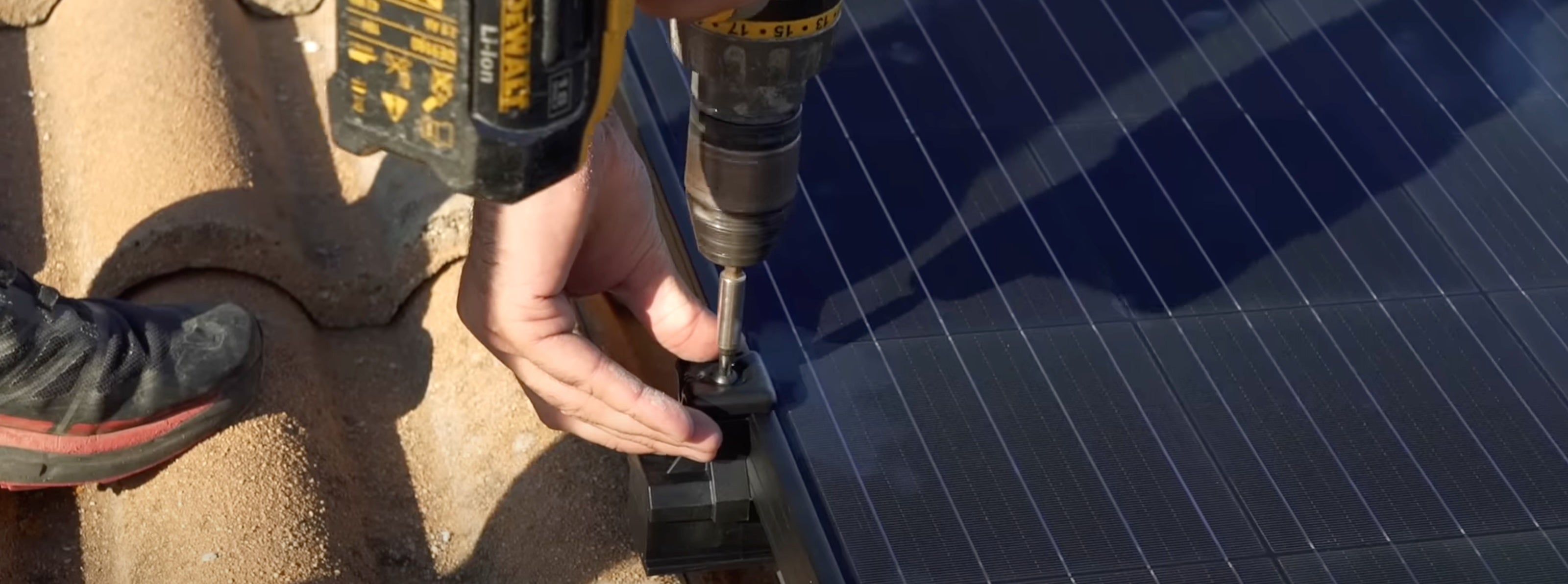 Un panneau solaire en train d'être installé a l'aide d'une visseuse